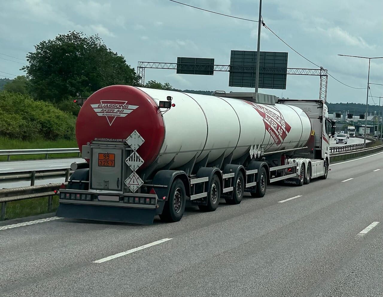 Svensk tankbil med orange ADR-skylt och faroetiketter på väg