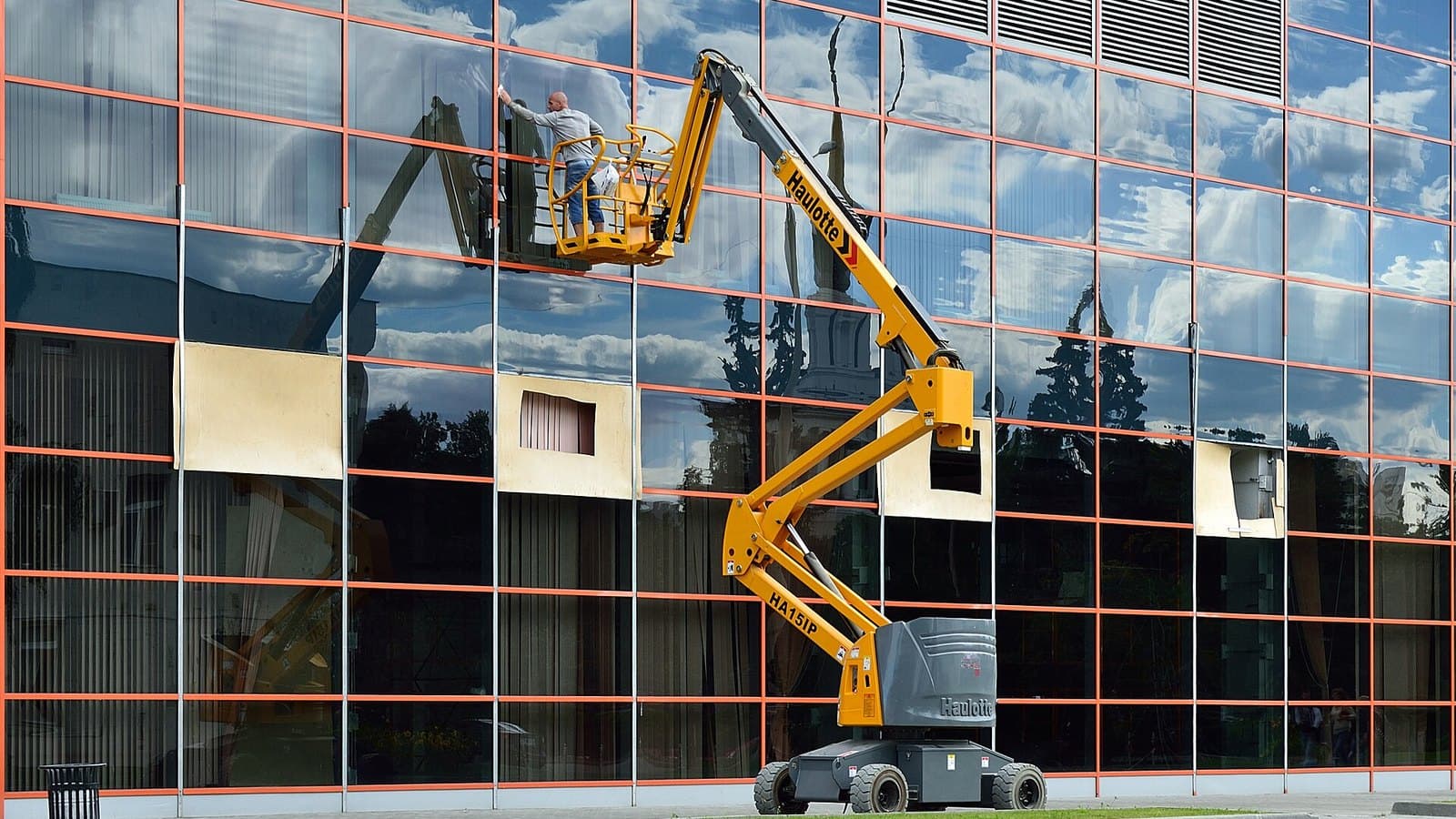 Bomlift med arbetare i korgen vid en fasad